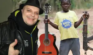 Mężczyzna w czarnym kapeluszu i chustce daje kciuk w górę. Obok chłopiec z gitarą i karabinem. Makumba tekst.