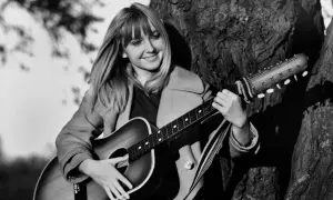 Maryla Rodowicz z gitarą, jakby śpiewała "Wielka woda", oparta o drzewo.