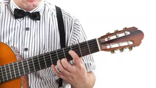 Mężczyzna w muszce i koszuli w paski gra na gitarze. Pokazuje, jak czytać tabulatury gitarowe, naciskając struny.