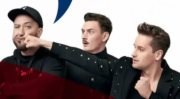 Trzech mężczyzn w czarnych strojach, jeden w czapce z daszkiem, przygotowuje się do męskiego grania. Orkiestra czeka na początek.