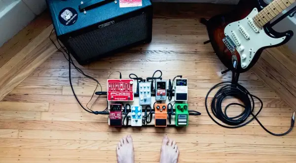 Gitarzysta przygotowuje się do sesji, jego stopa blisko pedałów efektowych. Wzmacniacz Fender i gitara elektryczna czekają na dźwięk.
