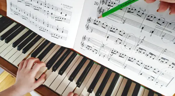 Dziecko uczy się grać na fortepianie, a zielony ołówek zaznacza nuty. Kto uczył Chopina grać na fortepianie? Może tak jak to dziecko, miał cierpliwego nauczyciela.