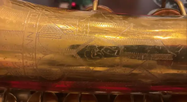 Złoty saksofon C.G. Conn z wygrawerowanym napisem i ornamentami.