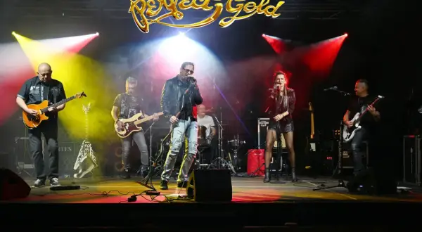 Zespół Perfect Gold gra na scenie, oświetlony kolorowymi światłami.
