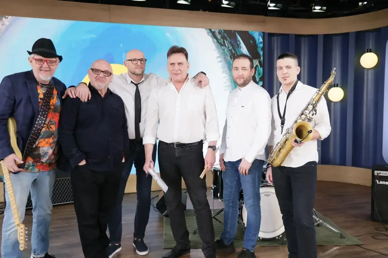 Zespół Mr. Zoob gotowy do występu. Muzycy w białych koszulach i jeansach, jeden z gitarą, drugi z saksofonem. "Mój jest ten kawałek podłogi" - tekst piosenki.
